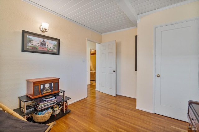 interior space featuring beamed ceiling, ornamental molding, and light wood-type flooring