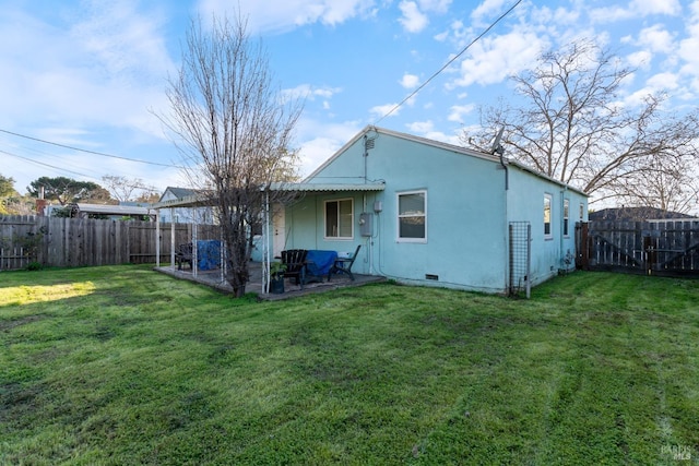 back of house with a lawn and a patio