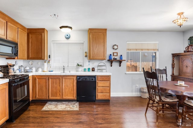 kitchen featuring tile counters, sink, dark wood-type flooring, and black appliances