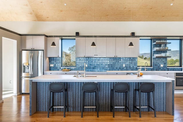 kitchen with pendant lighting, appliances with stainless steel finishes, an island with sink, and a breakfast bar area