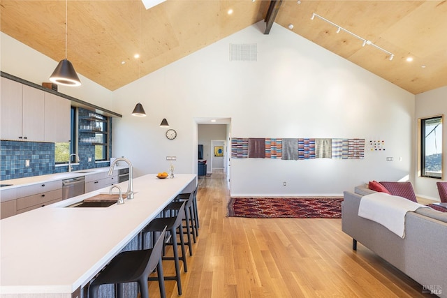 kitchen with hanging light fixtures, sink, backsplash, and high vaulted ceiling