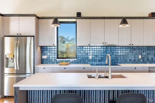 kitchen with stainless steel fridge with ice dispenser, sink, hanging light fixtures, and backsplash