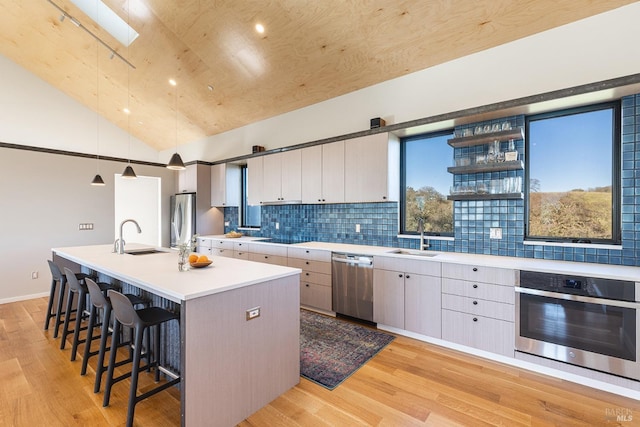 kitchen with sink, white cabinetry, decorative light fixtures, a center island with sink, and stainless steel appliances