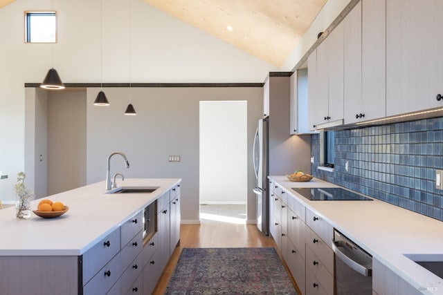 kitchen with sink, stainless steel appliances, tasteful backsplash, decorative light fixtures, and light wood-type flooring