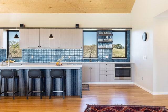 kitchen with pendant lighting, a kitchen bar, oven, and sink