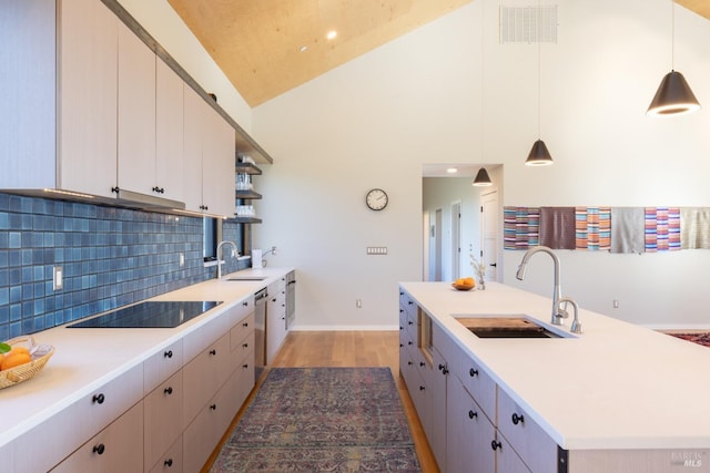 kitchen featuring vaulted ceiling, pendant lighting, an island with sink, sink, and black electric stovetop