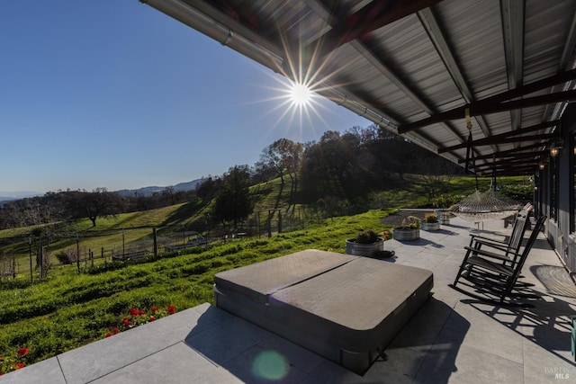 view of patio / terrace with a covered hot tub and a rural view