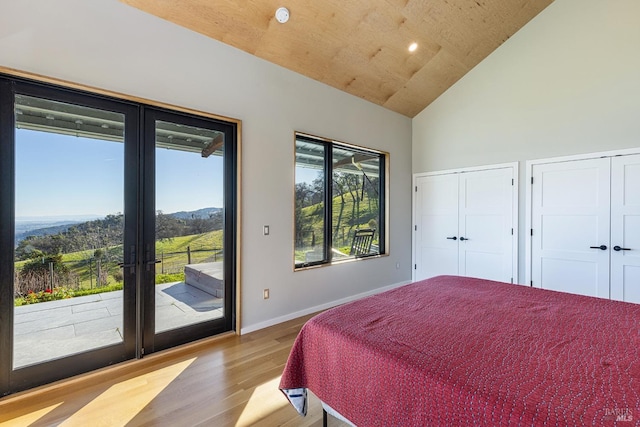 bedroom featuring french doors, wood ceiling, light wood-type flooring, multiple closets, and access to exterior