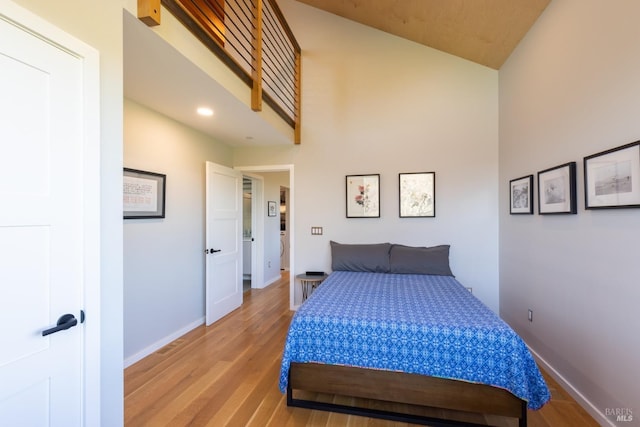 bedroom featuring high vaulted ceiling and light hardwood / wood-style flooring