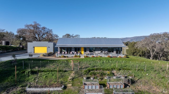 back of property with a rural view, a mountain view, a garage, and an outdoor structure