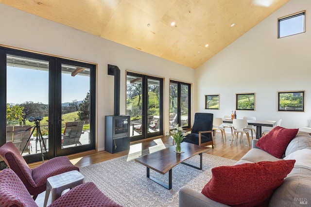 living room with light hardwood / wood-style floors, high vaulted ceiling, and french doors