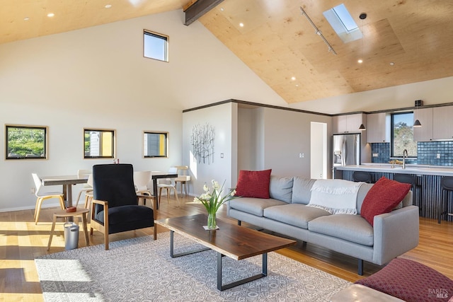 living room with beam ceiling, light hardwood / wood-style flooring, high vaulted ceiling, and a skylight