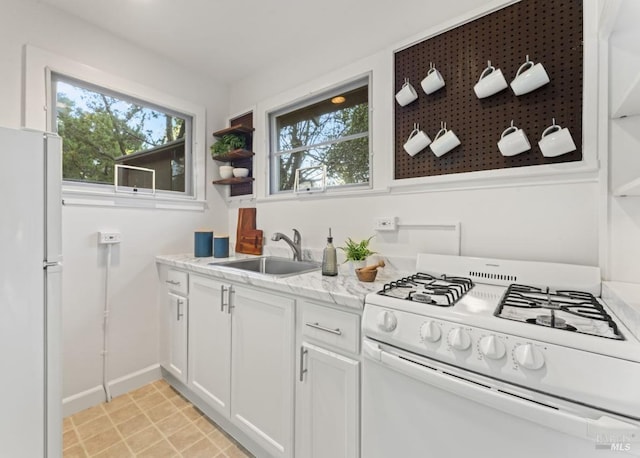 kitchen featuring sink, white cabinets, light tile patterned floors, light stone countertops, and white appliances