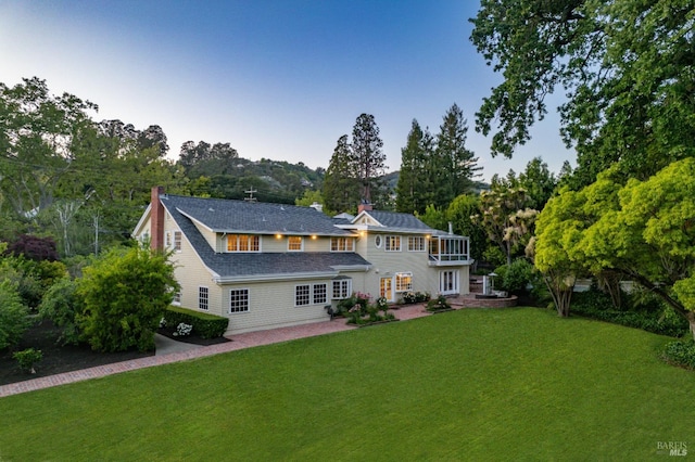 rear view of property featuring a balcony and a lawn