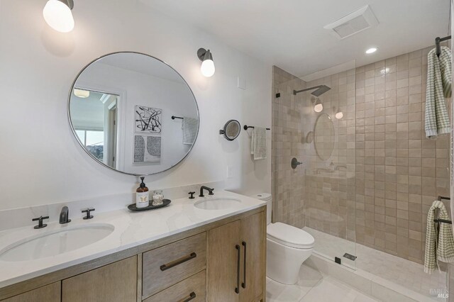 bathroom with tile patterned floors, toilet, vanity, and a tile shower