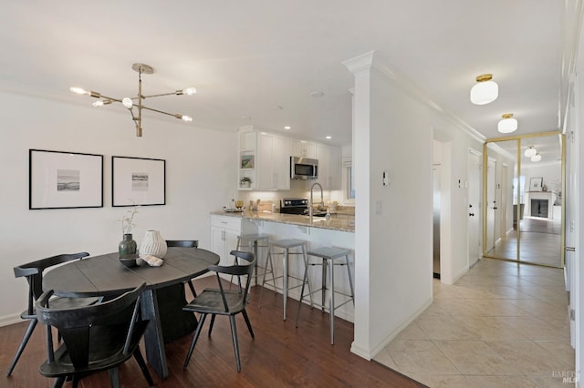 dining room with sink, light tile patterned floors, ornamental molding, and a chandelier