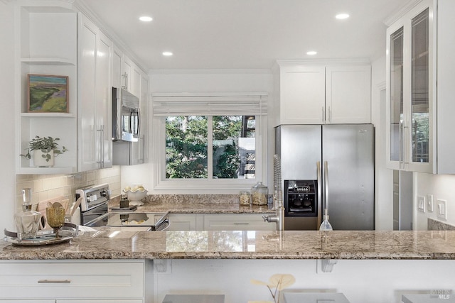 kitchen with white cabinetry, light stone counters, and appliances with stainless steel finishes