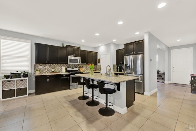 kitchen featuring decorative backsplash, light tile patterned floors, appliances with stainless steel finishes, and a sink