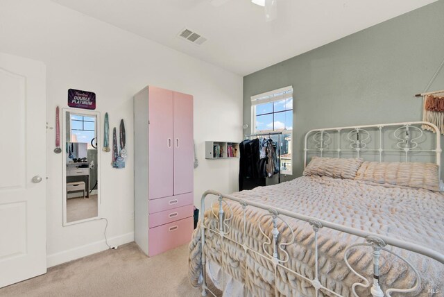 bedroom with visible vents, baseboards, light colored carpet, and ceiling fan