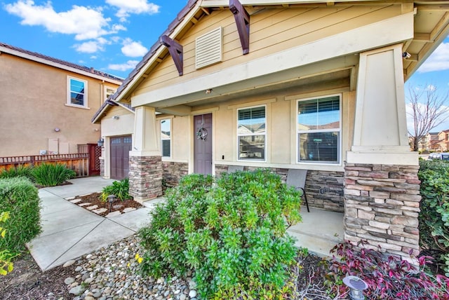 view of front facade with a garage, fence, stone siding, and stucco siding