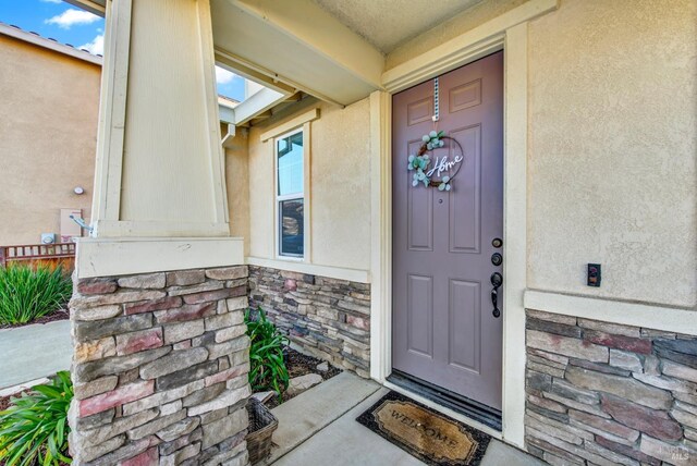 doorway to property featuring stucco siding and stone siding