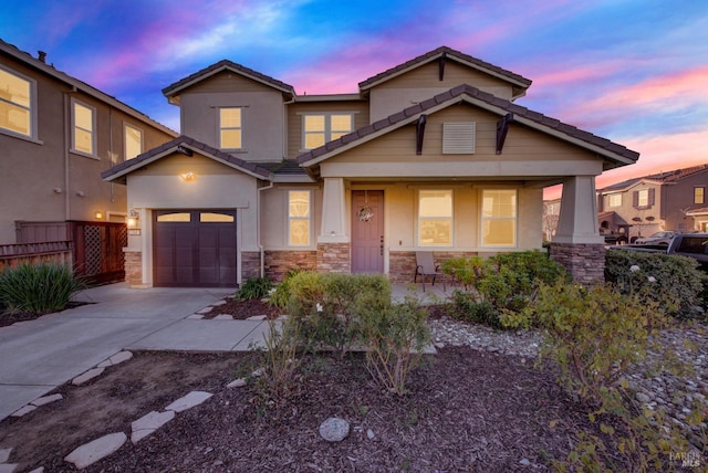 view of front of property with stucco siding, driveway, stone siding, fence, and a tiled roof