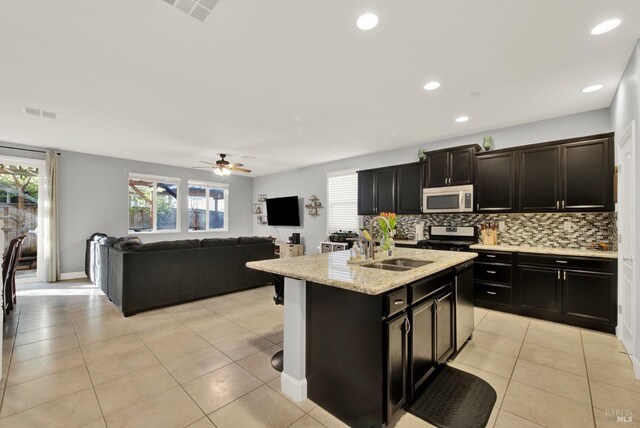 kitchen featuring visible vents, a sink, stainless steel appliances, open floor plan, and backsplash