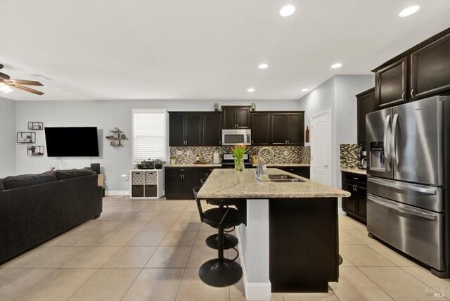 kitchen with backsplash, open floor plan, light tile patterned flooring, stainless steel appliances, and a sink