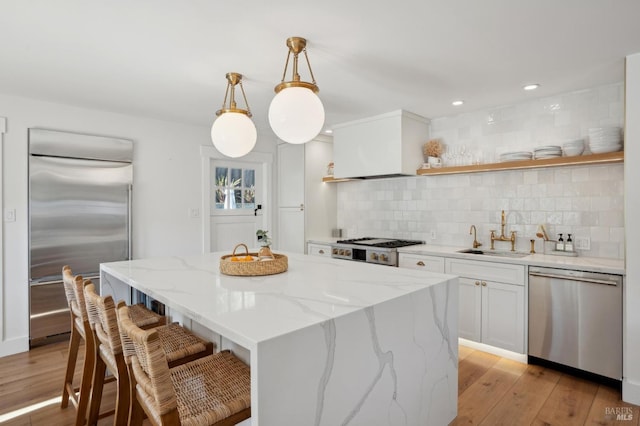 kitchen featuring sink, appliances with stainless steel finishes, white cabinetry, decorative backsplash, and decorative light fixtures