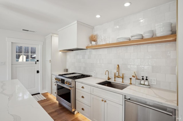 kitchen with sink, stainless steel appliances, light stone countertops, decorative backsplash, and custom exhaust hood