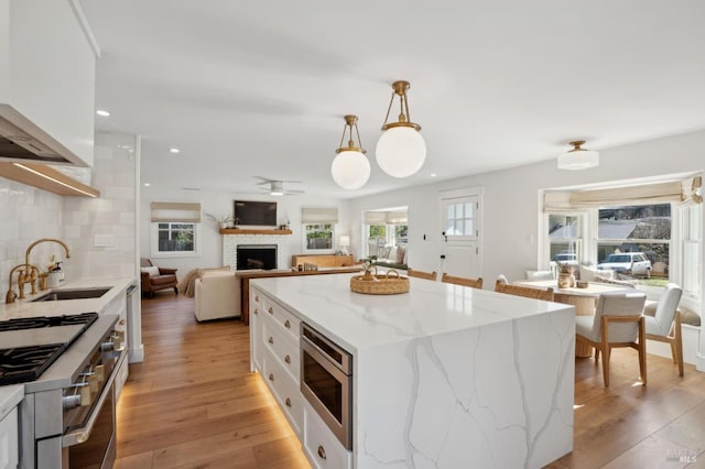 kitchen with a kitchen island, appliances with stainless steel finishes, decorative light fixtures, white cabinetry, and backsplash