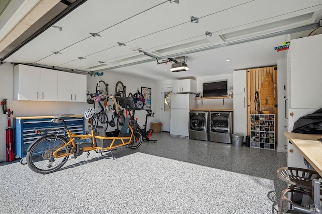 garage featuring washing machine and clothes dryer, a garage door opener, and white fridge