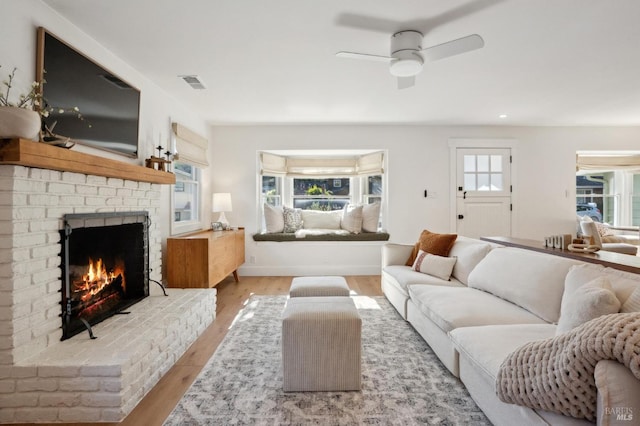 living room with a fireplace, light hardwood / wood-style floors, and ceiling fan