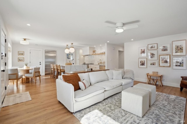 living room featuring ceiling fan, sink, and light hardwood / wood-style flooring