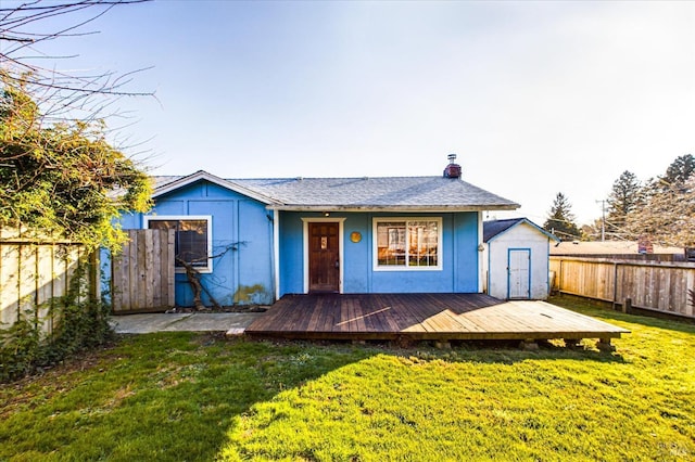 back of house with a storage shed, a deck, and a lawn