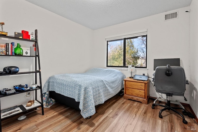 bedroom with wood-type flooring and a textured ceiling