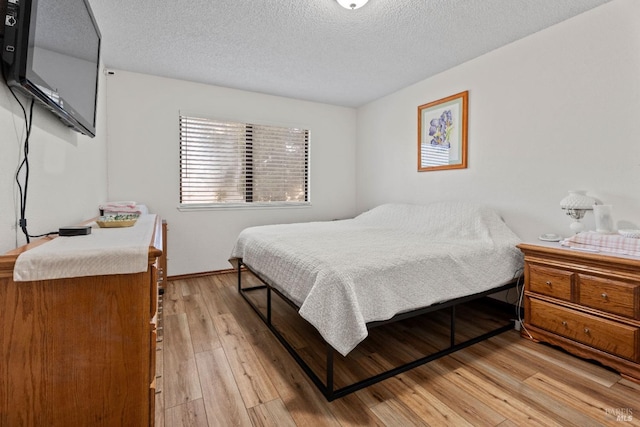 bedroom with a textured ceiling and light wood-type flooring