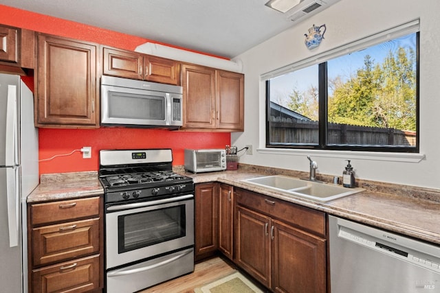 kitchen with sink, stainless steel appliances, and light hardwood / wood-style floors