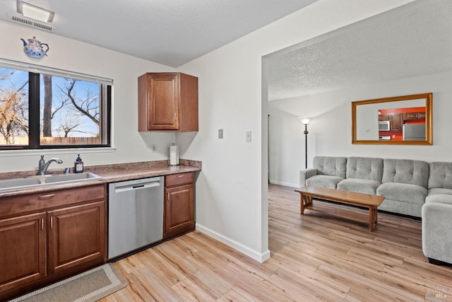 kitchen with stainless steel appliances, sink, a textured ceiling, and light hardwood / wood-style flooring