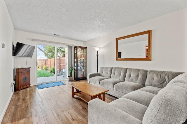 living room with a textured ceiling and light hardwood / wood-style flooring