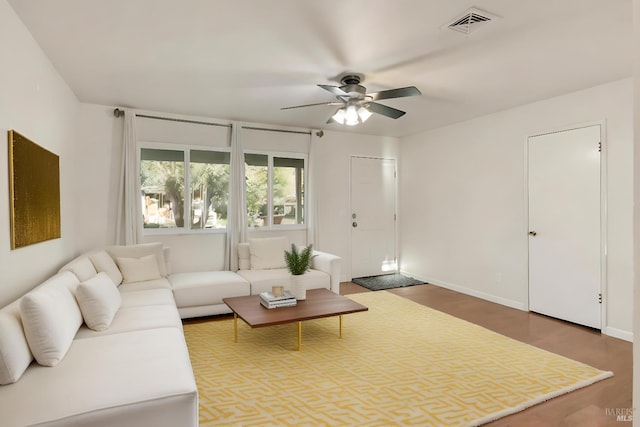 living area with ceiling fan, visible vents, baseboards, and wood finished floors