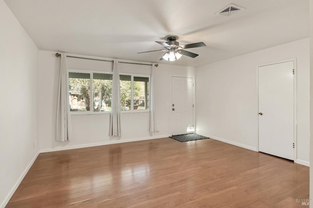 empty room featuring visible vents, ceiling fan, baseboards, and wood finished floors