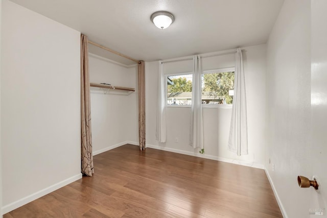 unfurnished bedroom with a closet, baseboards, and wood finished floors