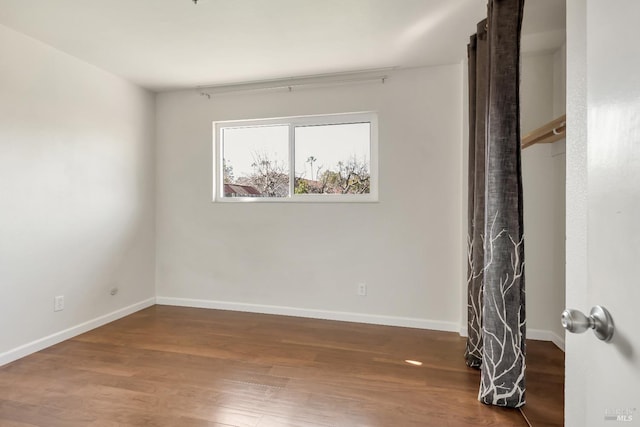 empty room with baseboards and wood finished floors