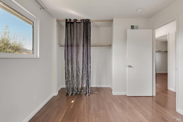 unfurnished bedroom featuring wood finished floors, visible vents, and baseboards