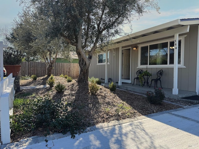 view of front of house with covered porch, fence, and board and batten siding