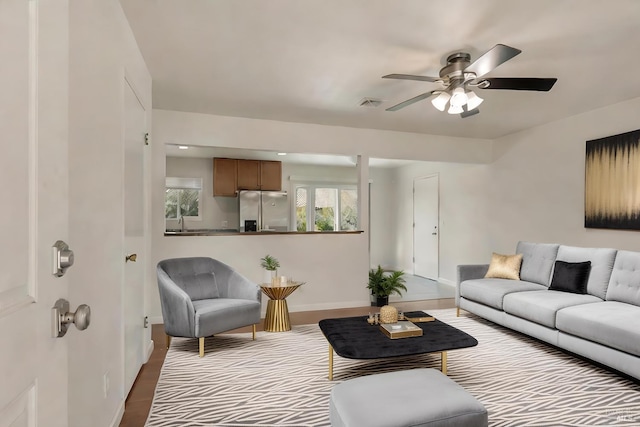 living room featuring visible vents, baseboards, a ceiling fan, and wood finished floors