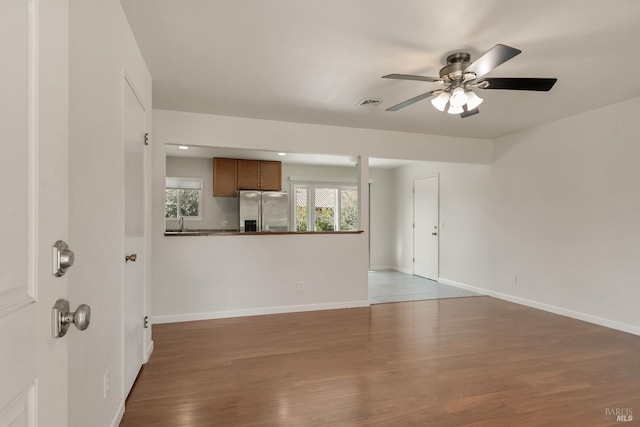 unfurnished living room with visible vents, baseboards, ceiling fan, wood finished floors, and a sink