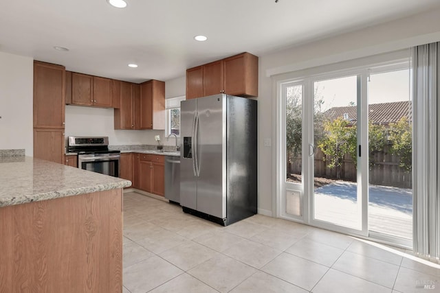 kitchen featuring light tile patterned flooring, recessed lighting, stainless steel appliances, a sink, and brown cabinets