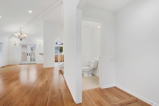 hall featuring a notable chandelier, light hardwood / wood-style floors, and french doors